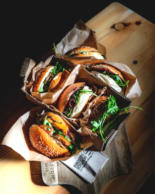 Burger in Papier auf einem Holzbrett von Bordsteinschwalbe – Foodfotografie aus Neuss