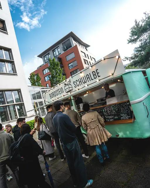 Gäste stehen am Foodtruck von Bordsteinschwalbe bei einem Firmenevent